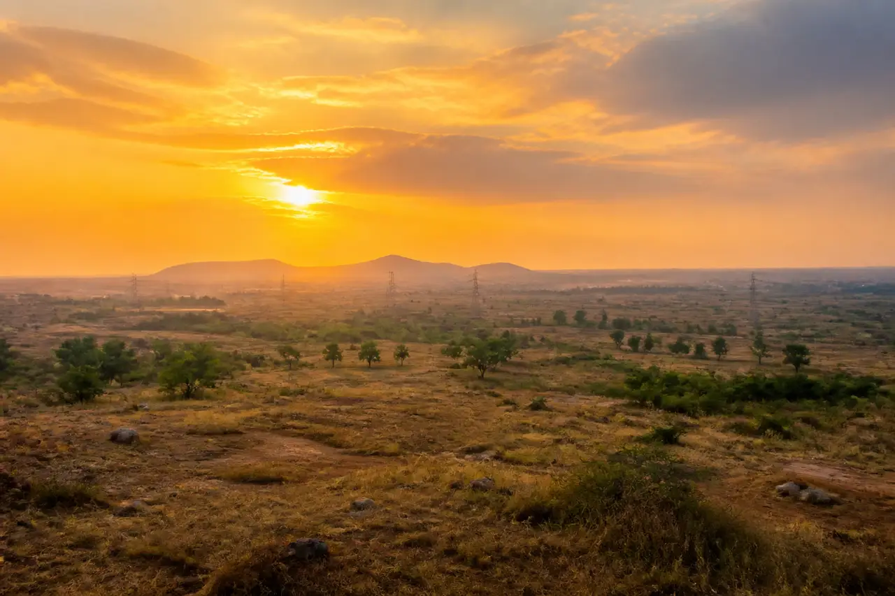 Golden evening light across open terrain and distant low hills